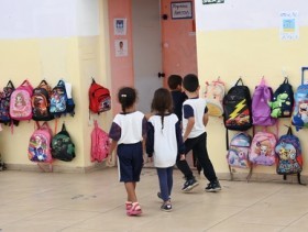 Imagem de 4 crianças uniformizadas em pátio de uma escola municipal.